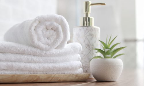 close up ofTowel placed on the basket, white tabletop, bottle of liquid soap, spa set for bathing in the bathroom, copy space, bathroom window.